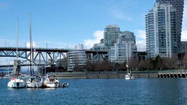 Bridge to greenville and water bus passing under the bridge Nature Canada Vancouver Pacific Ocean Pier and pillars on the pier Granville Island aquabus Skyscrapers in the background 2023 Canada