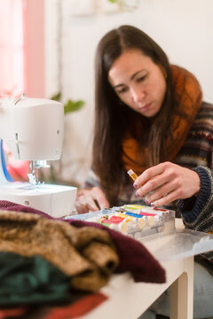 Woman choosing sewing threads at home