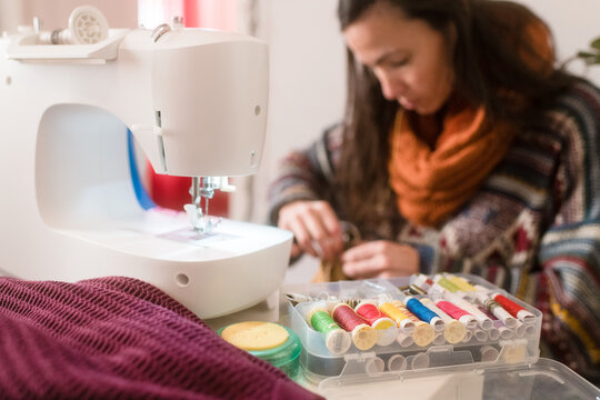 Detail of colour threads with woman sewing in background