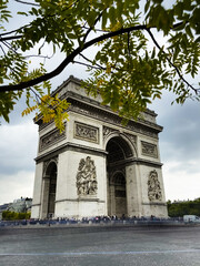 Fototapeta na wymiar Arc de Triomphe l Paris l France in the Afternoon with Cloudy Skies and Visiting Tourists.