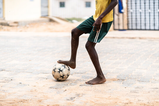 Crop child kicking ball on street - Powered by Adobe