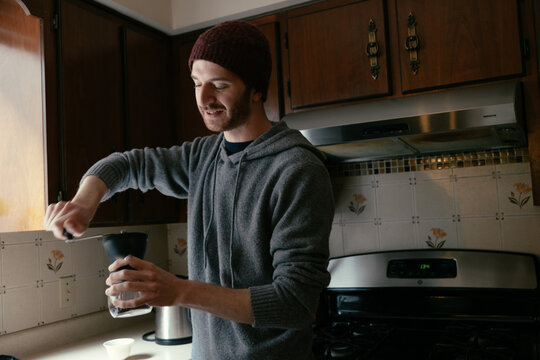 Man grinding coffee beans in kitchen.