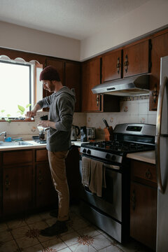 Man grinding coffee beans in kitchen.