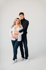 a blonde pregnant woman with a man in black and white clothes hugging