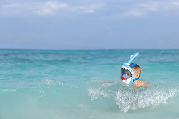 A little boy in a full face mask is snorkeling in the Maldives