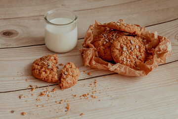 Oatmeal cookies with milk on light background with crumbs