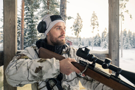 Hunter holding rifle looking around