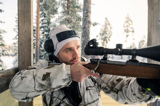 Hunter aiming rifle in snow