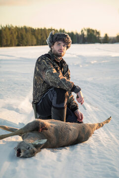 Hunter butchering deer looking at camera