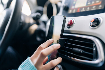 Crop woman using smartphone while driving car
