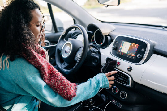 Crop woman using smartphone while driving car
