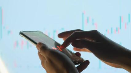 Broker or investor monitors the dynamics of the stock price or cryptocurrency on a smartphone, close-up