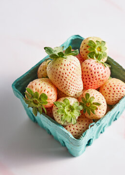 Arranged pineberries (white strawberries) on pink marble background