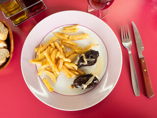 plate of fried black pudding blood sausage and french fries,small bottle of olive oil, and bran...