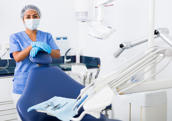 Portrait of professional qualified woman dentist posing with arms crossed at modern dental clinic..