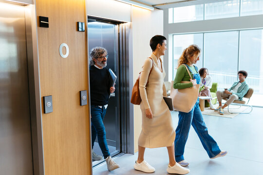Business people walking out of elevator in office