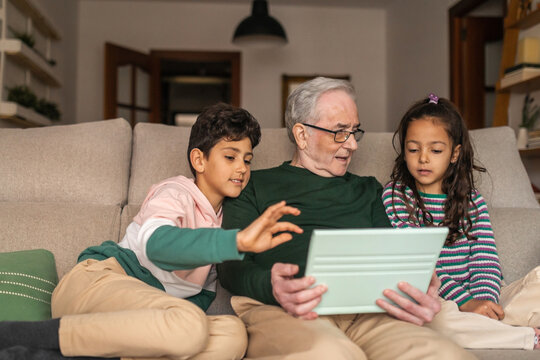 grandfather with his two grandchildren using ipad at home