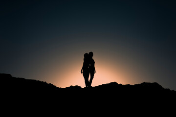 Lesbian couple silhouettes together at sunset