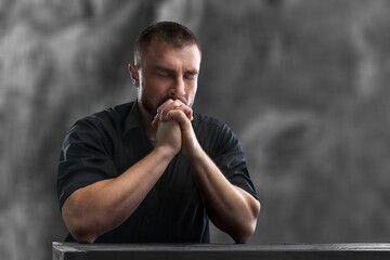 Young man praying at the table. Religion concept.