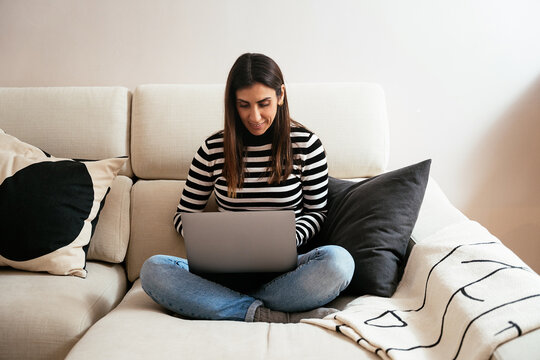 Focused woman working on computer on couch