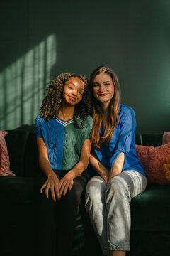 friends leaning against each other sitting on green sofa 