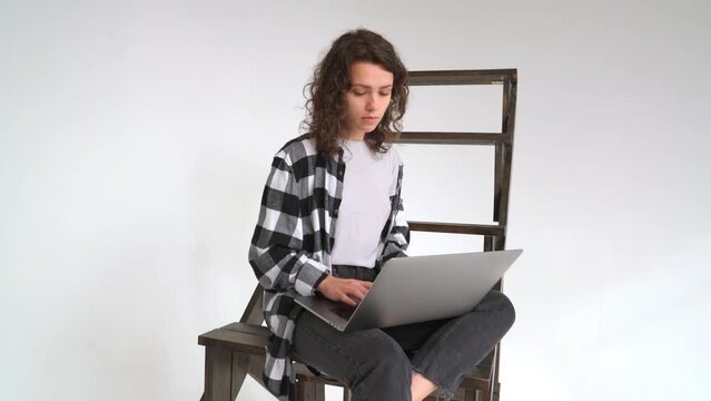 Young woman freelancer distant work with laptop. Busy girl writing with a computer. Person sit in cafe on the stairs. Freelance people web study indoor. Digital nomad