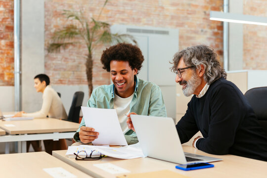 Cheerful diverse colleagues working on project in office