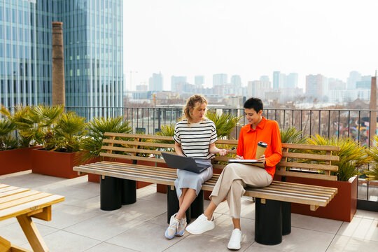 Female colleagues working together sitting in building terrace