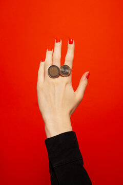 Hand with red nails with rings made of coins