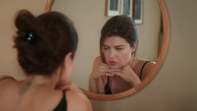 Elegant young woman in a black dress admiring herself in mirror and straightens hair.
Positive self image. Love yourself and feel feminine. Girl going on a date. Relieve stress