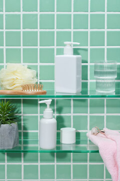 Shelf with bath accessories near mosaic wall