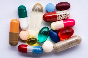 Flat lay composition with different colorful pills. Pile of medication on white paper. Close up.