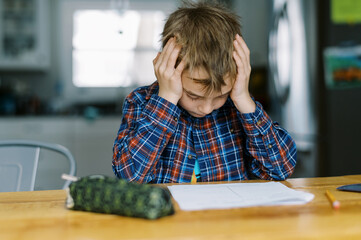 little boy at home sitting at dining table doing his homework
