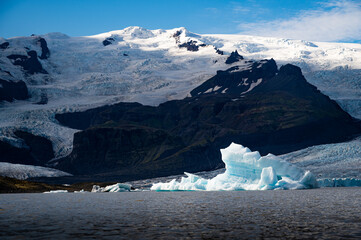 Lonely iceberg floating on Fjallsarlon, Fjallsjokull glacier in the back, Iceland