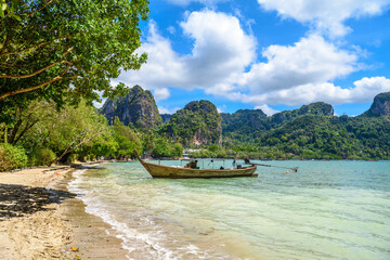 Obraz premium Long boats, rocks and cliffs covered with tropical trees, azure water on Ao Phra Nang Beach, Railay east Ao Nang, Krabi, Thailand