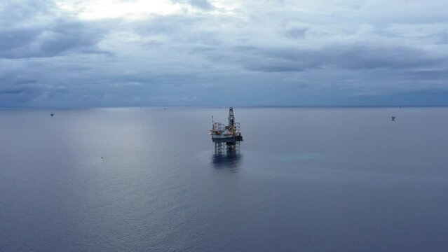 Jack up drilling rig and production platform in the middle of the ocean during couldy time
