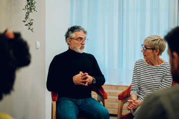 Senior man psychologist on a group therapy session discussing mental health issues
