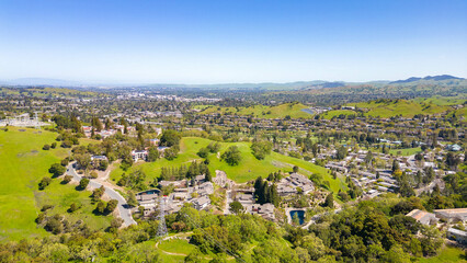 Fototapeta na wymiar A stunning drone photo captures the Rossmoor community's picturesque beauty, showcasing homes, a golf course, green hills, and a clear blue sky.