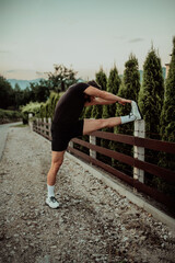 Athlete performing leg stretching exercises after a run in a natural environment. Fitness themed photograph showcasing physical activity flexibility and health.