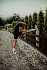 Athlete performing leg stretching exercises after a run in a natural environment. Fitness themed photograph showcasing physical activity flexibility and health.