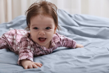 Cute little baby in pajamas on bed indoors. Space for text