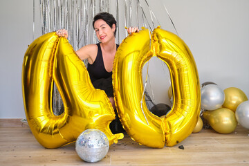 Caucasian woman in a 40 birthday party with 40 birthday golden balloons on the floor.