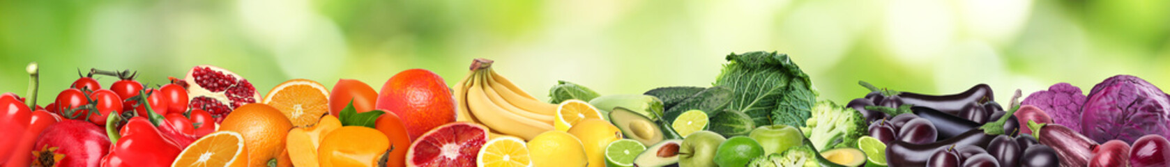 Many different fresh fruits and vegetables against blurred green background. Banner design