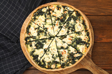 Delicious homemade spinach quiche on wooden table, top view