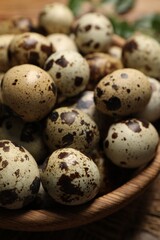 Obraz premium Wooden bowl with quail eggs on table, closeup