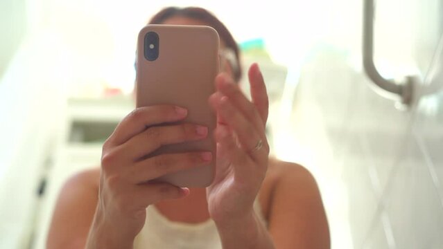 woman using the phone while sitting on the toilet