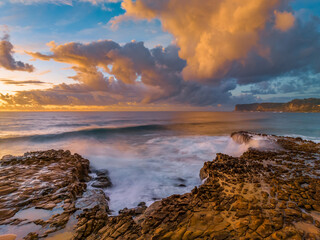 Obraz premium Sunrise and clouds over the ocean and rock platform