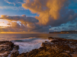 Sunrise and clouds over the ocean and rock platform