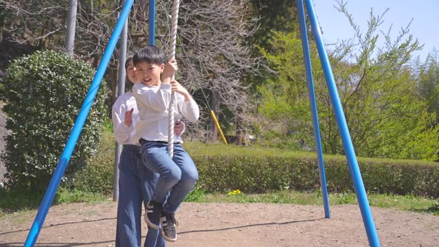 桜が咲く公園で遊ぶ日本人の男の子と女の子