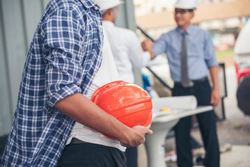 Contractor construction engineer meeting talking together on architect table at construction office site. Businessman engineer manager discuss with foreman team builder look at plan blueprint laptop